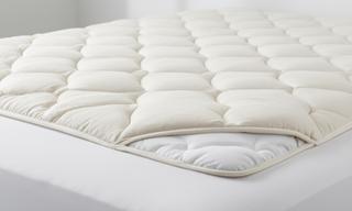 Quilted hypoallergenic mattress protector laid across a clean white mattress