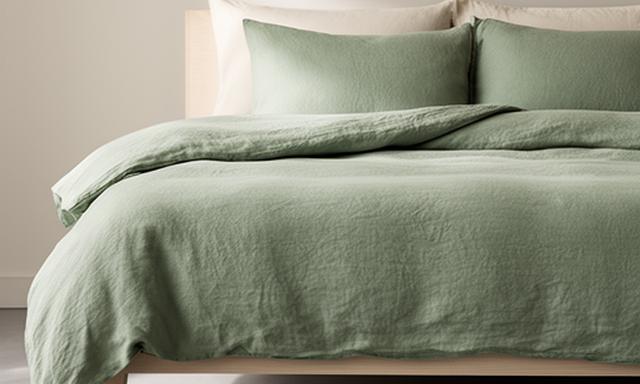 Sage green linen duvet cover folded at the foot of a simple modern bed